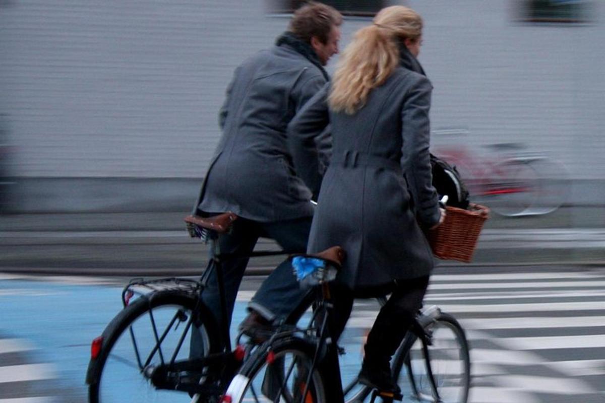 um homem e uma mulher andando de bicicleta pela rua