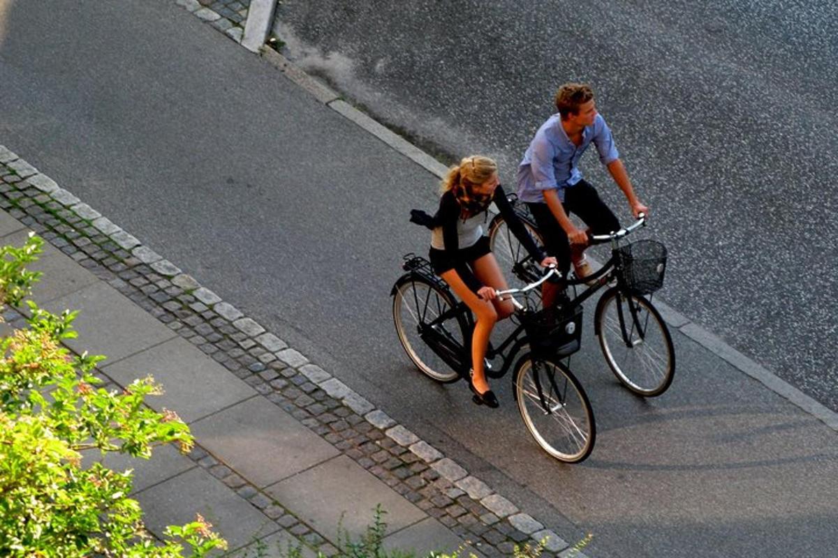 um homem e uma mulher andando de bicicleta pela rua