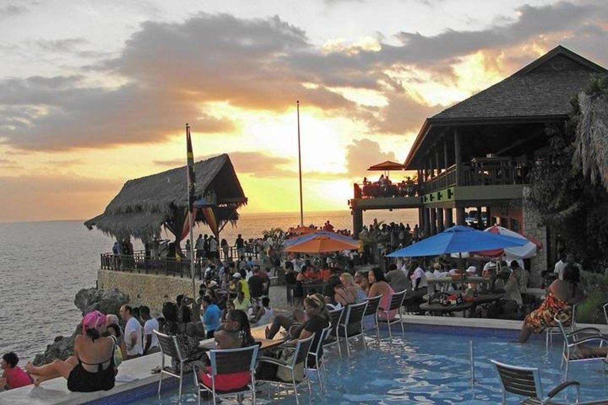 un grup de oameni care stau în jurul unei piscine lângă ocean