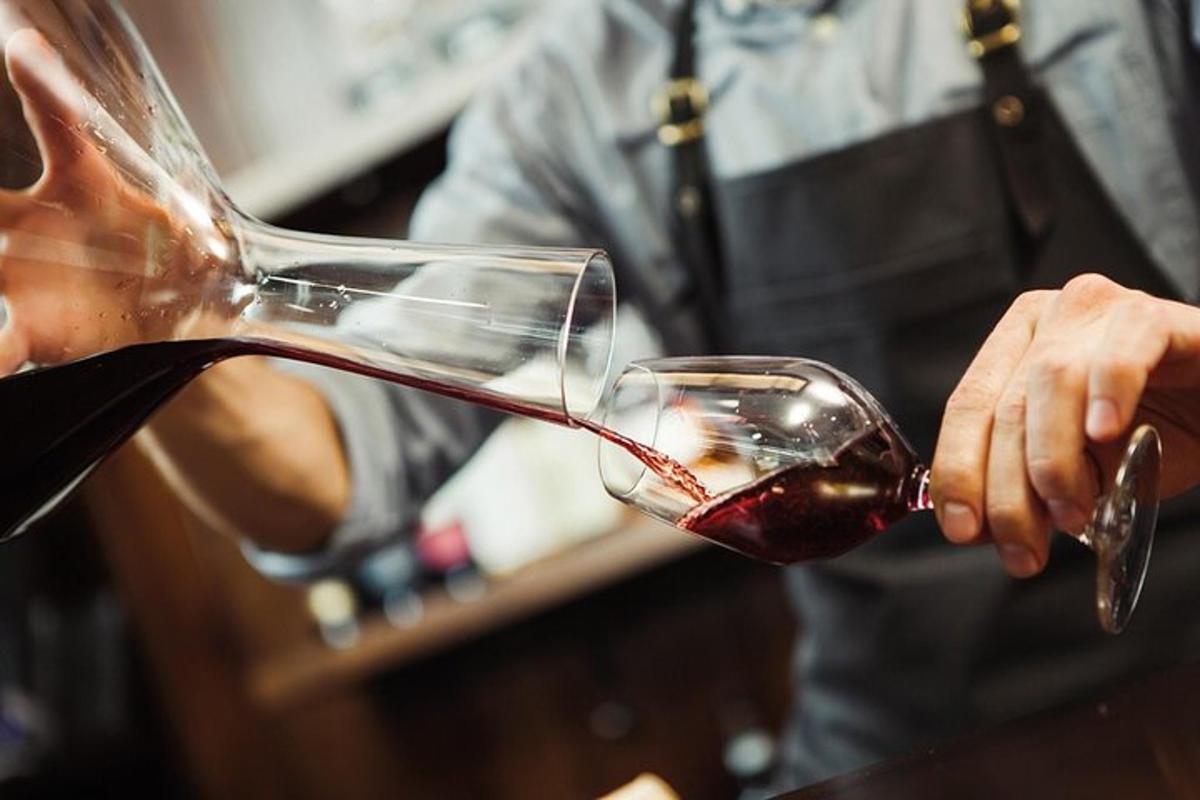 uma pessoa despejando vinho tinto em uma taça