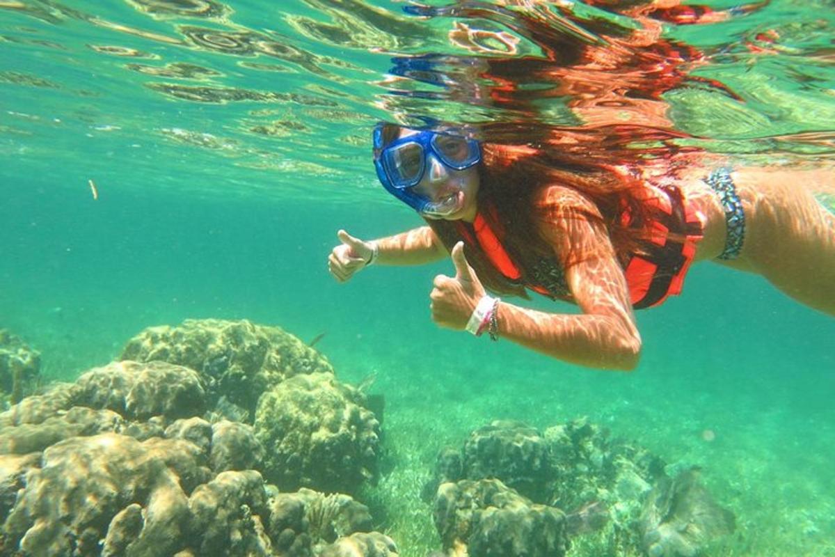 eine Frau im Wasser zeigt auf ein Riff