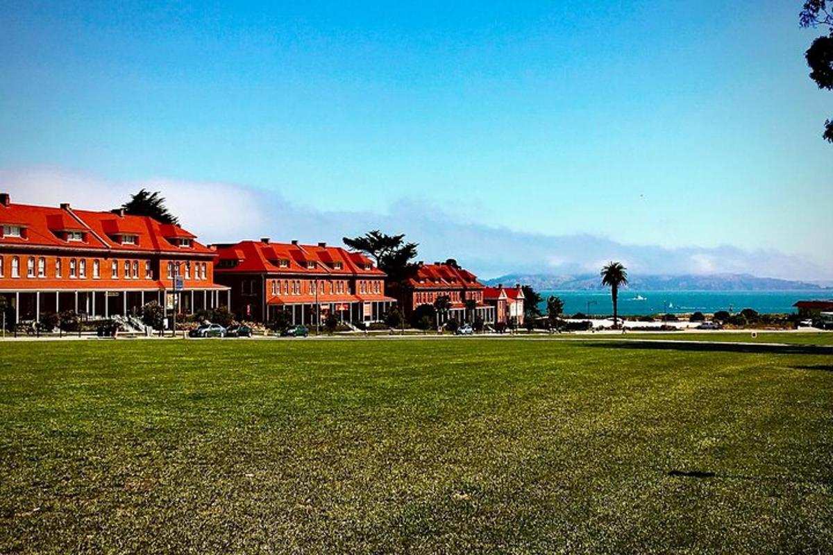 a group of buildings with red roofs and a grass field