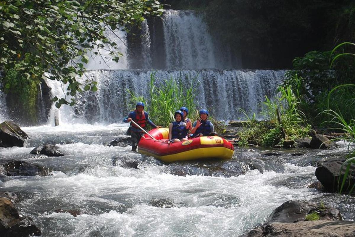 three people in a raft in a river with a waterfall