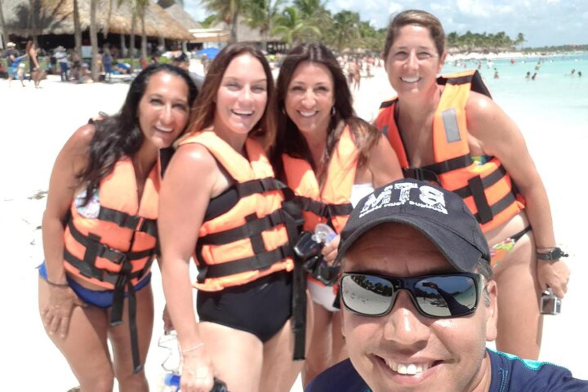 Un grupo de cuatro mujeres con chalecos salvavidas en la playa.