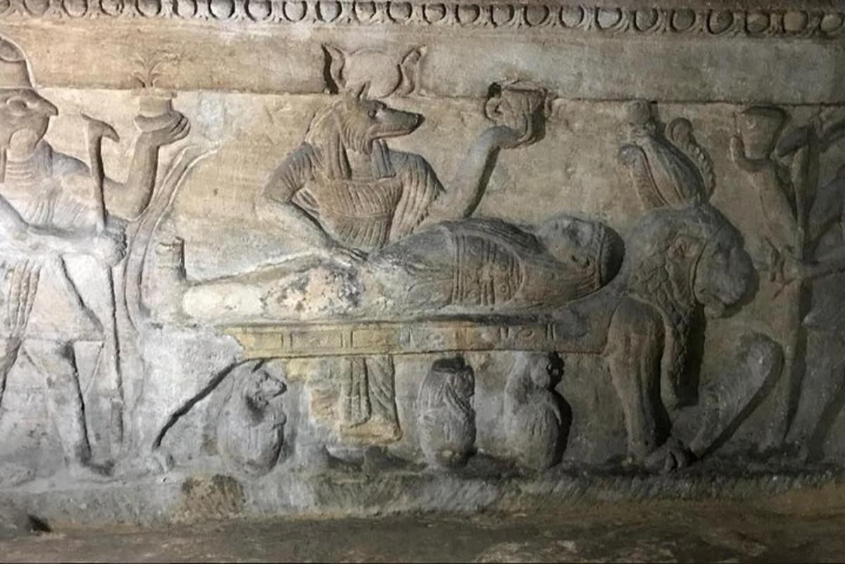 un zid de piatră cu un basorelief al unui bărbat întins pe o masă