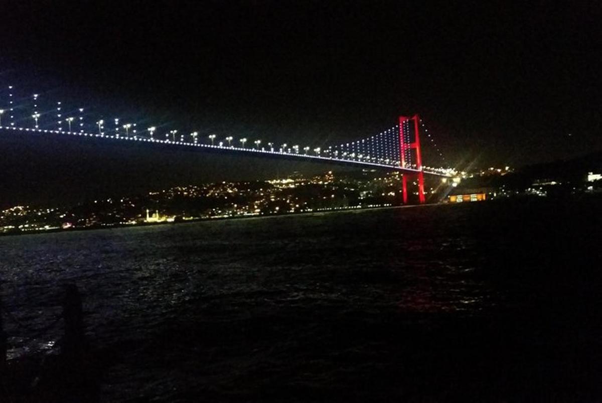 un ponte illuminato di notte con una città