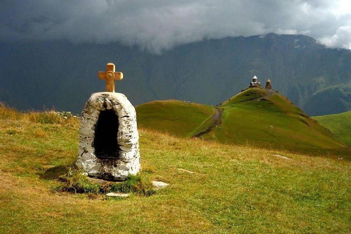 una croce in cima a una collina con una montagna