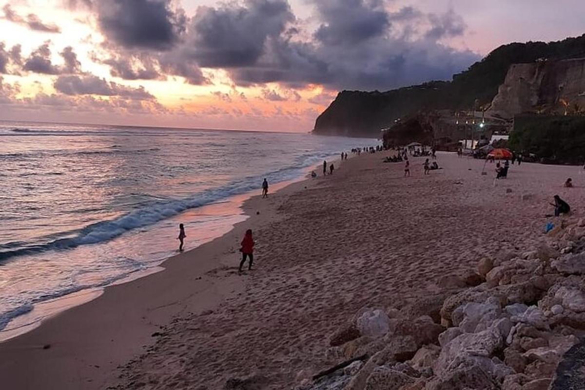 un grupo de personas en una playa al atardecer