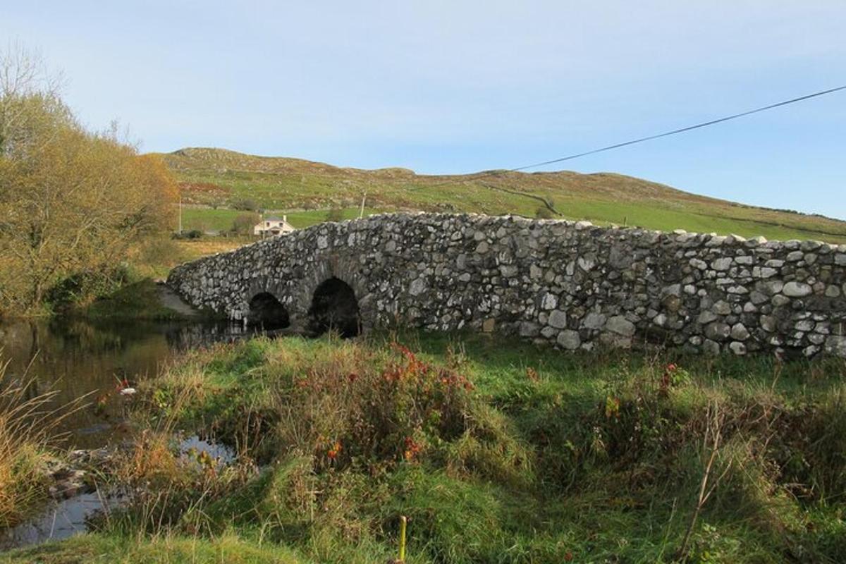 un pont de pierre sur une rivière dans un champ