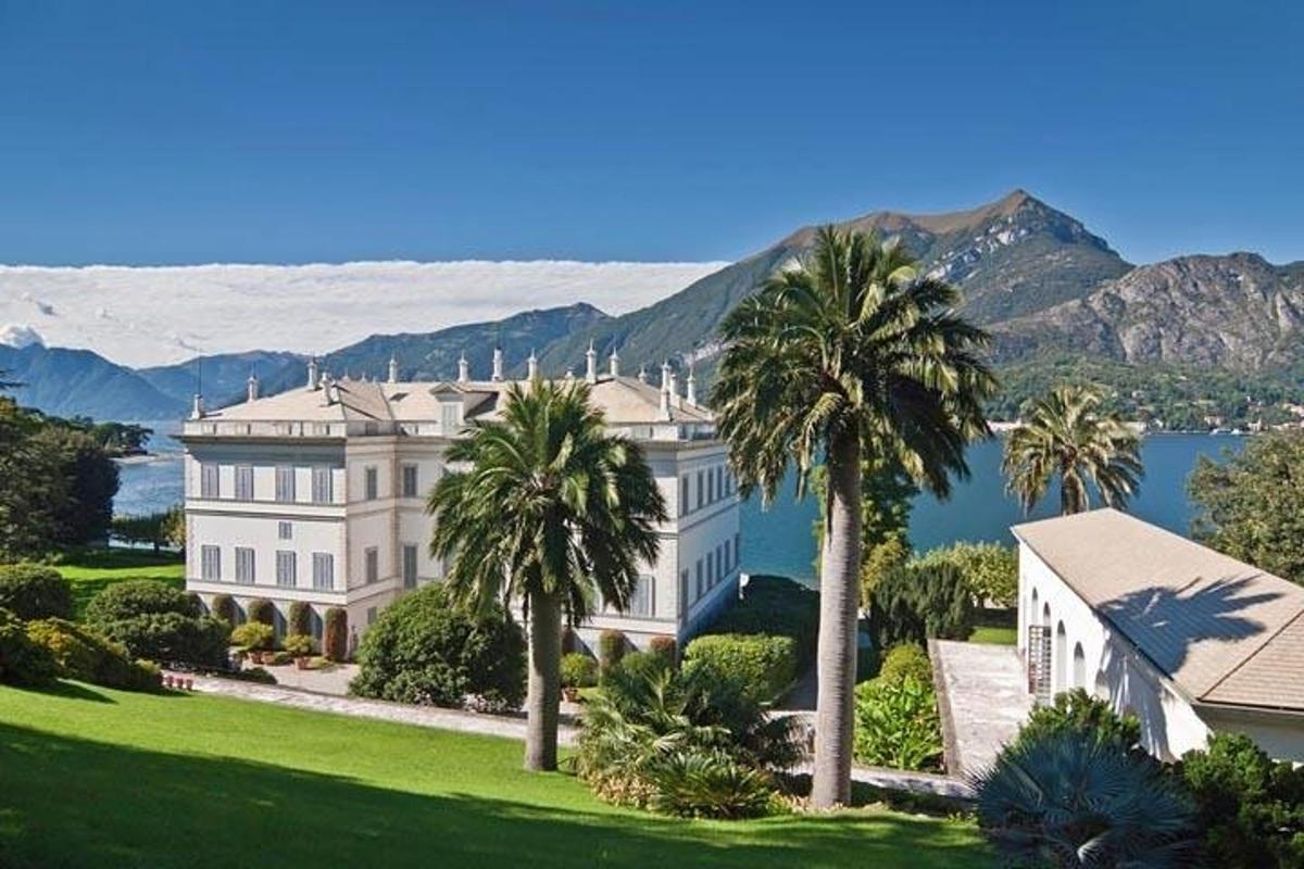 una grande villa con palme di fronte a uno specchio d'acqua