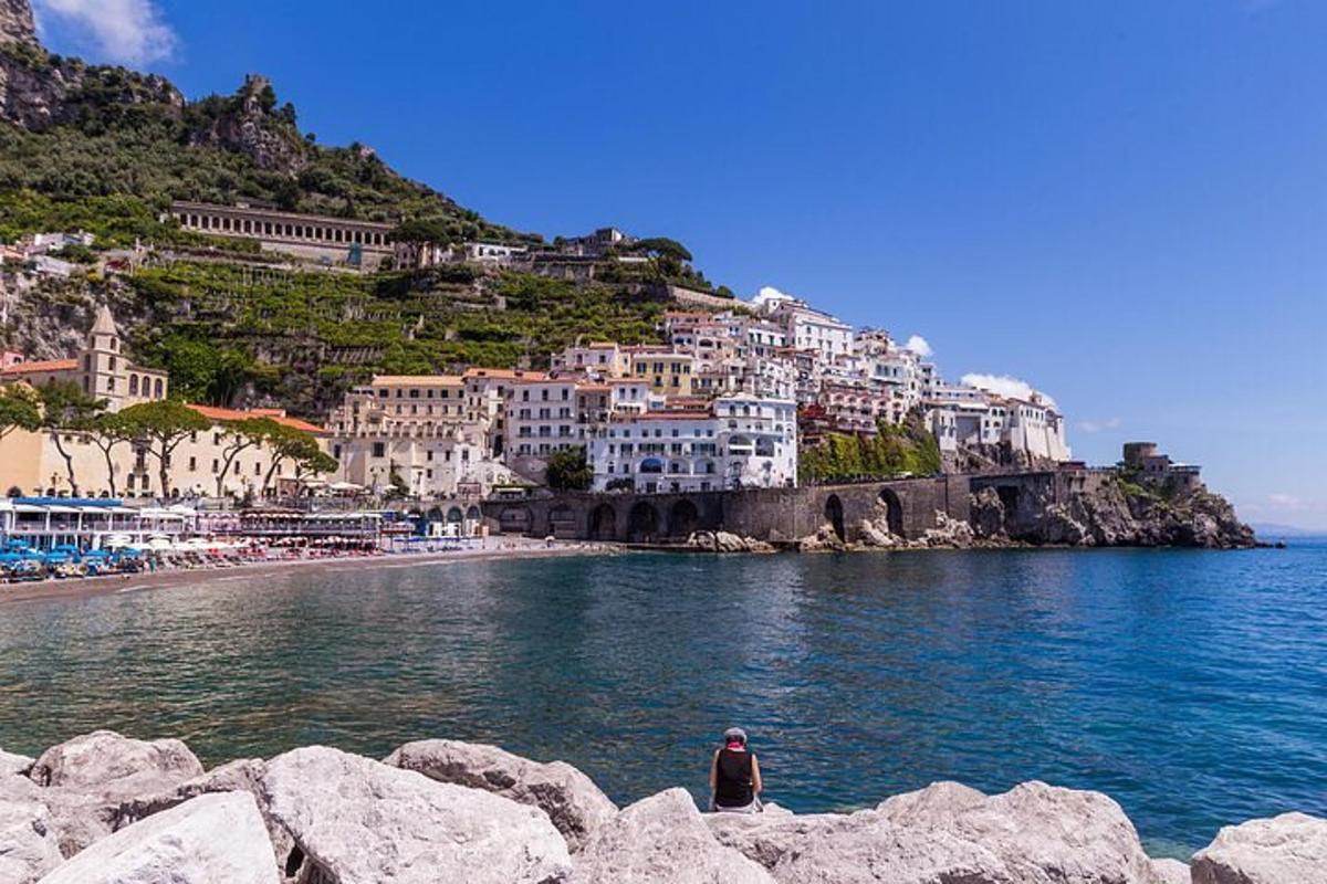 una persona seduta su una roccia vicino all'acqua