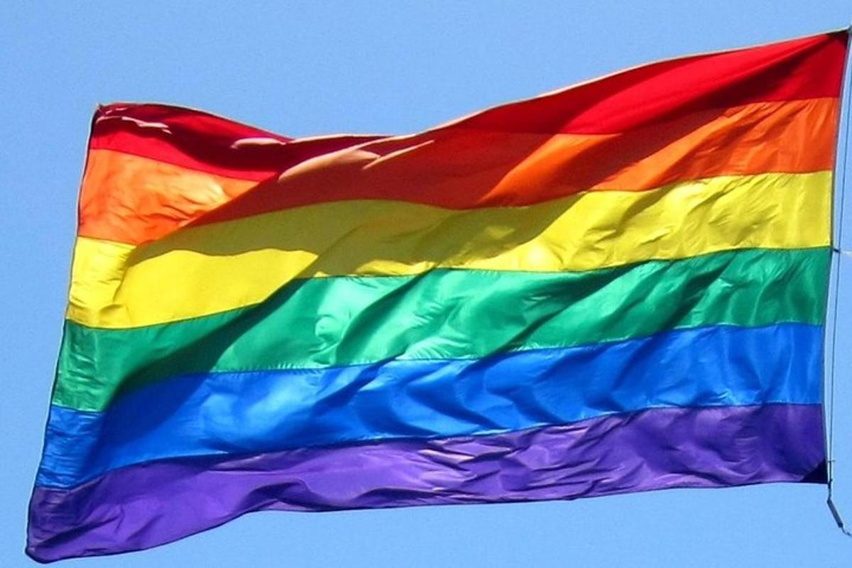a rainbow colored flag flying in the sky