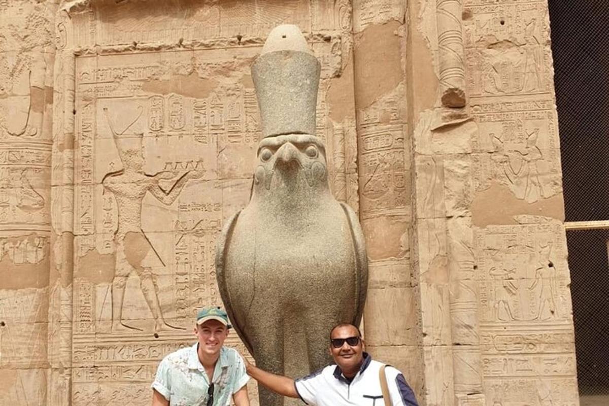 dois homens estão parados em frente a uma estátua