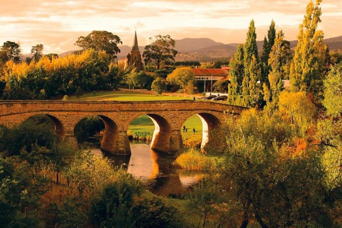 un ponte sopra un fiume con alberi e una chiesa