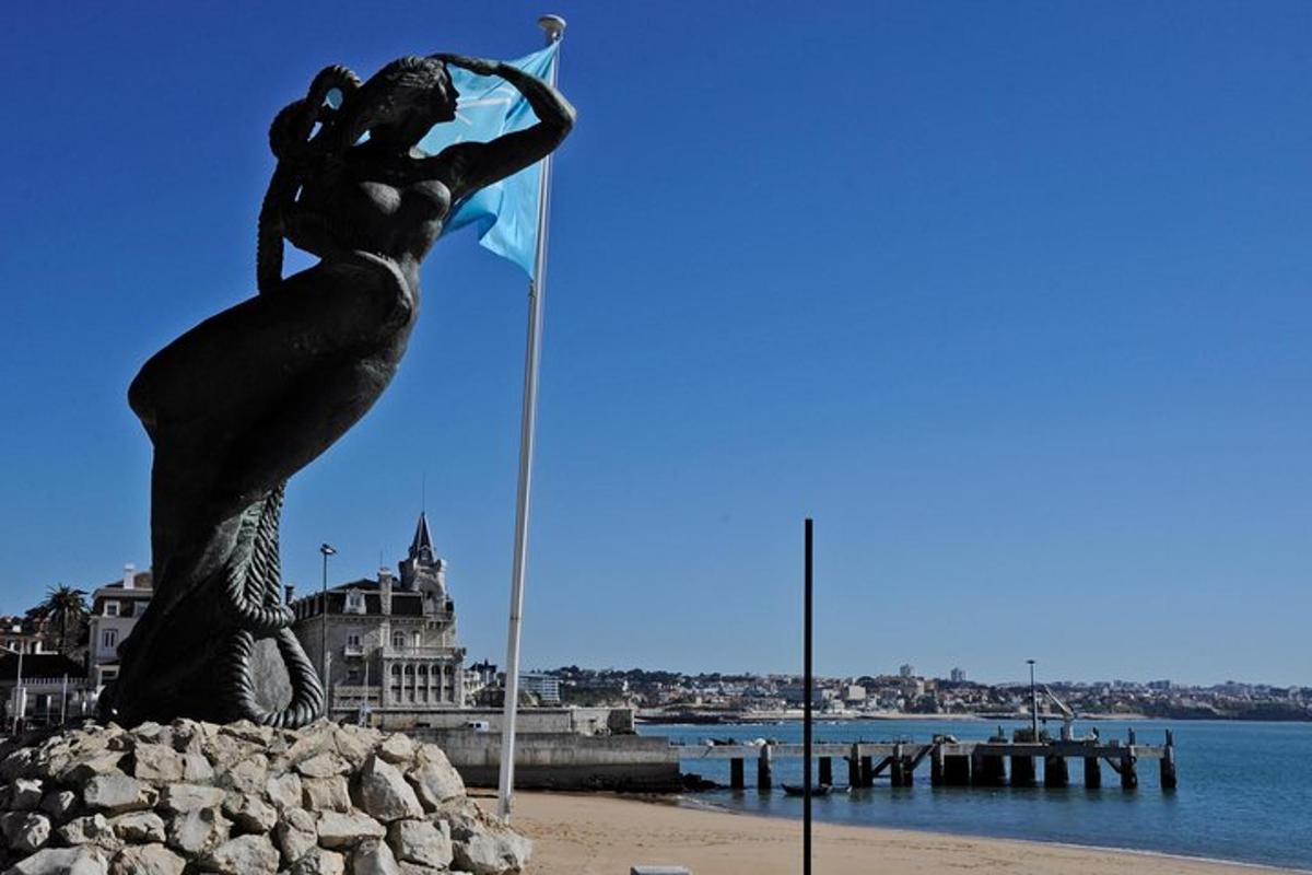 en statue av en havfrue på en strand nær vannet