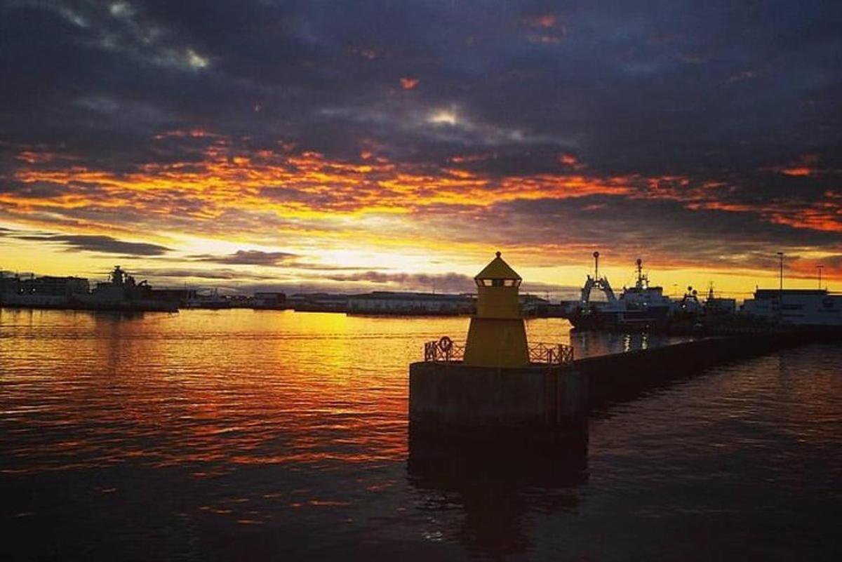 um farol em uma doca na água com um pôr do sol