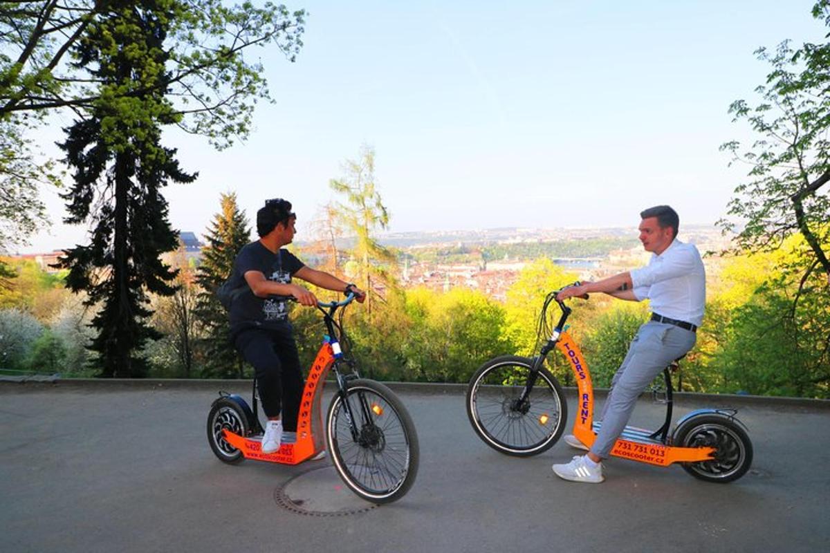 dva muži jedoucí na oranžových skútrech po ulici