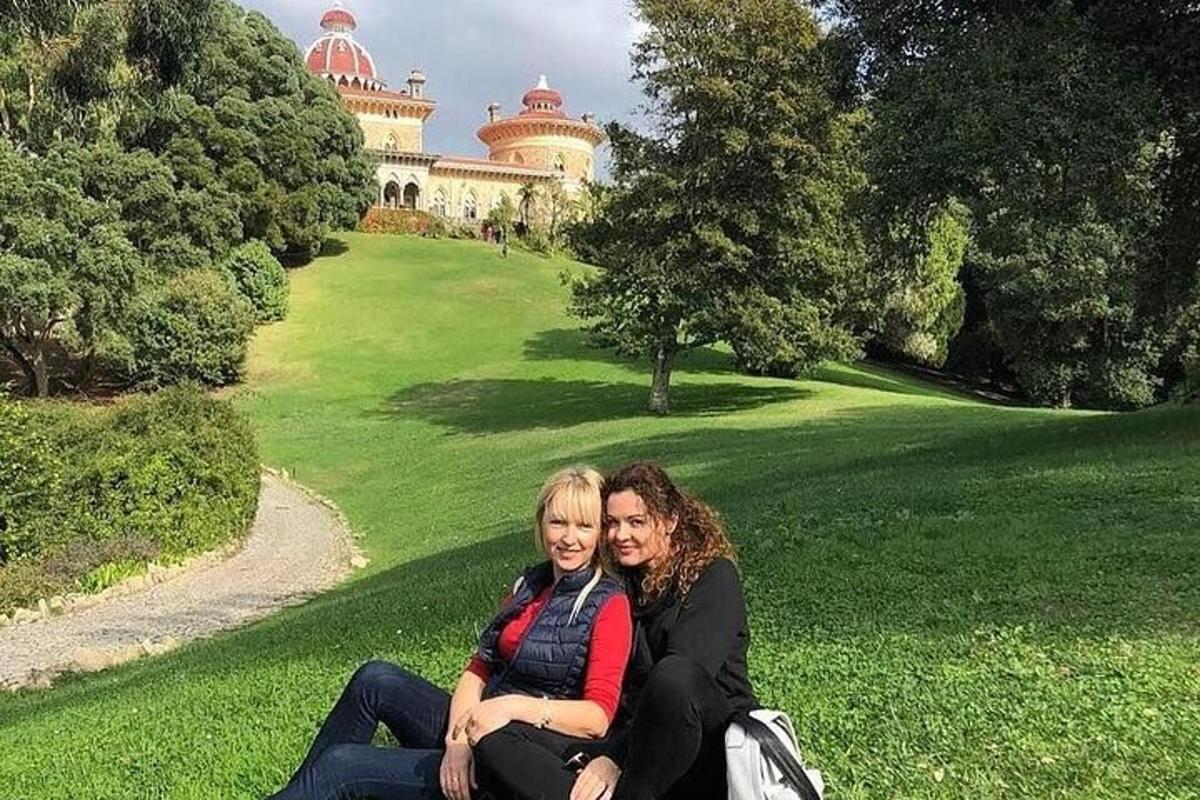 dvě ženy sedící na trávě před budovou