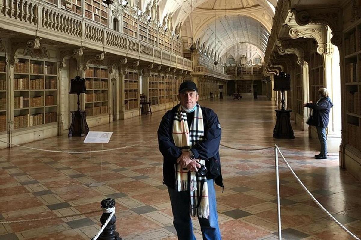 un uomo in piedi in una biblioteca con un cane