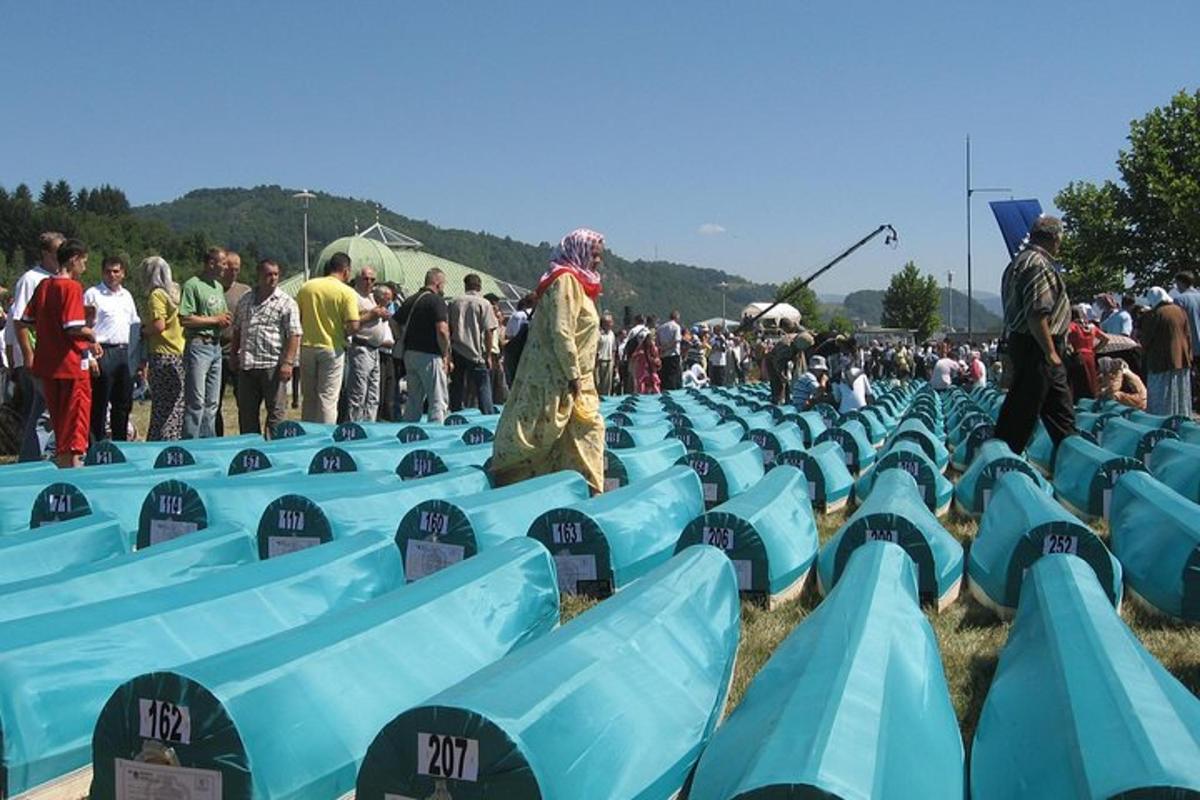 Una multitud de personas de pie alrededor de filas de asientos azules.