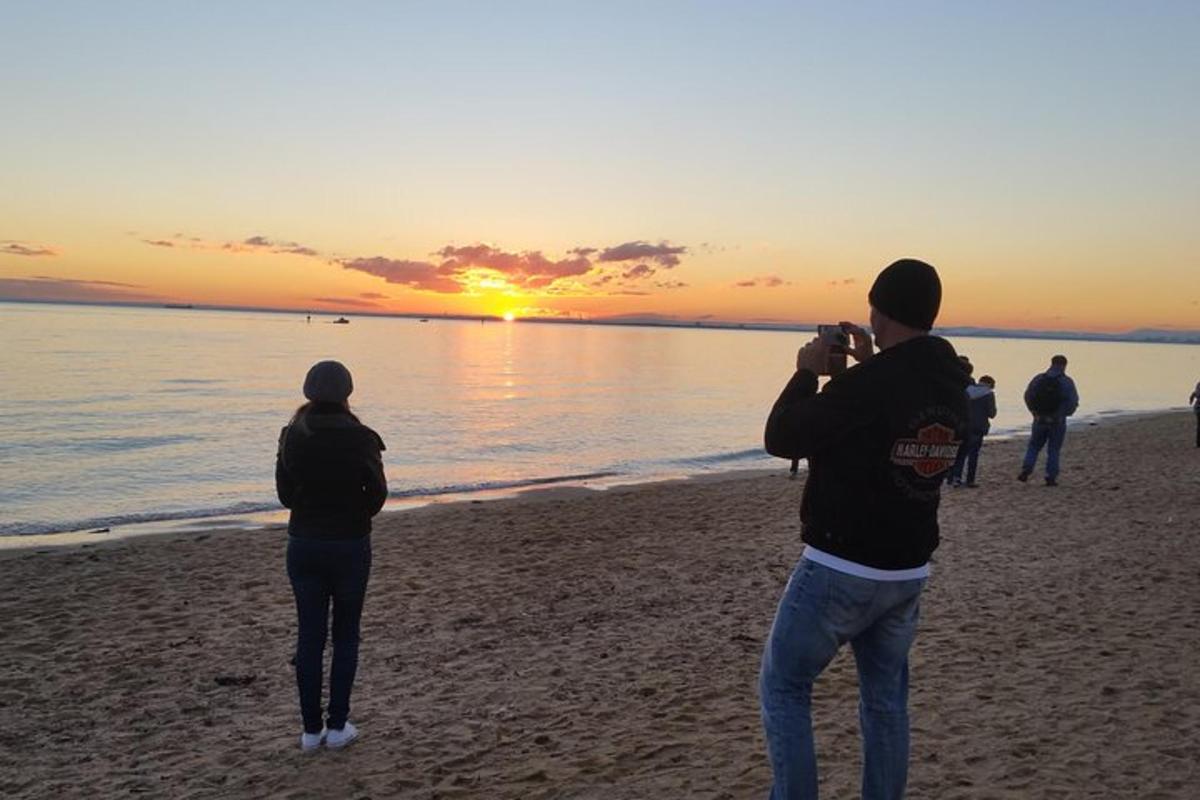 seorang lelaki mengambil gambar matahari terbenam di pantai