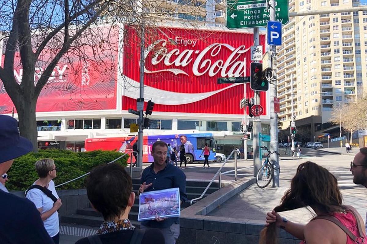 un gruppo di persone in piedi davanti a un cartello della Coca-Cola