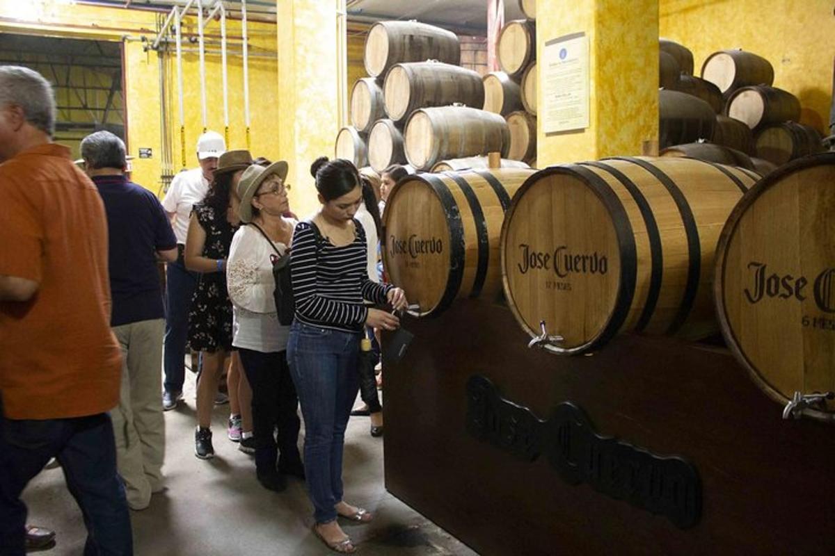 Un grupo de personas de pie alrededor de barriles de vino.