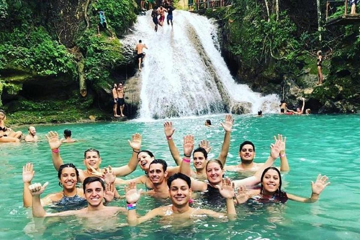 eine Gruppe von Menschen, die in einem Pool vor einem Wasserfall schwimmen