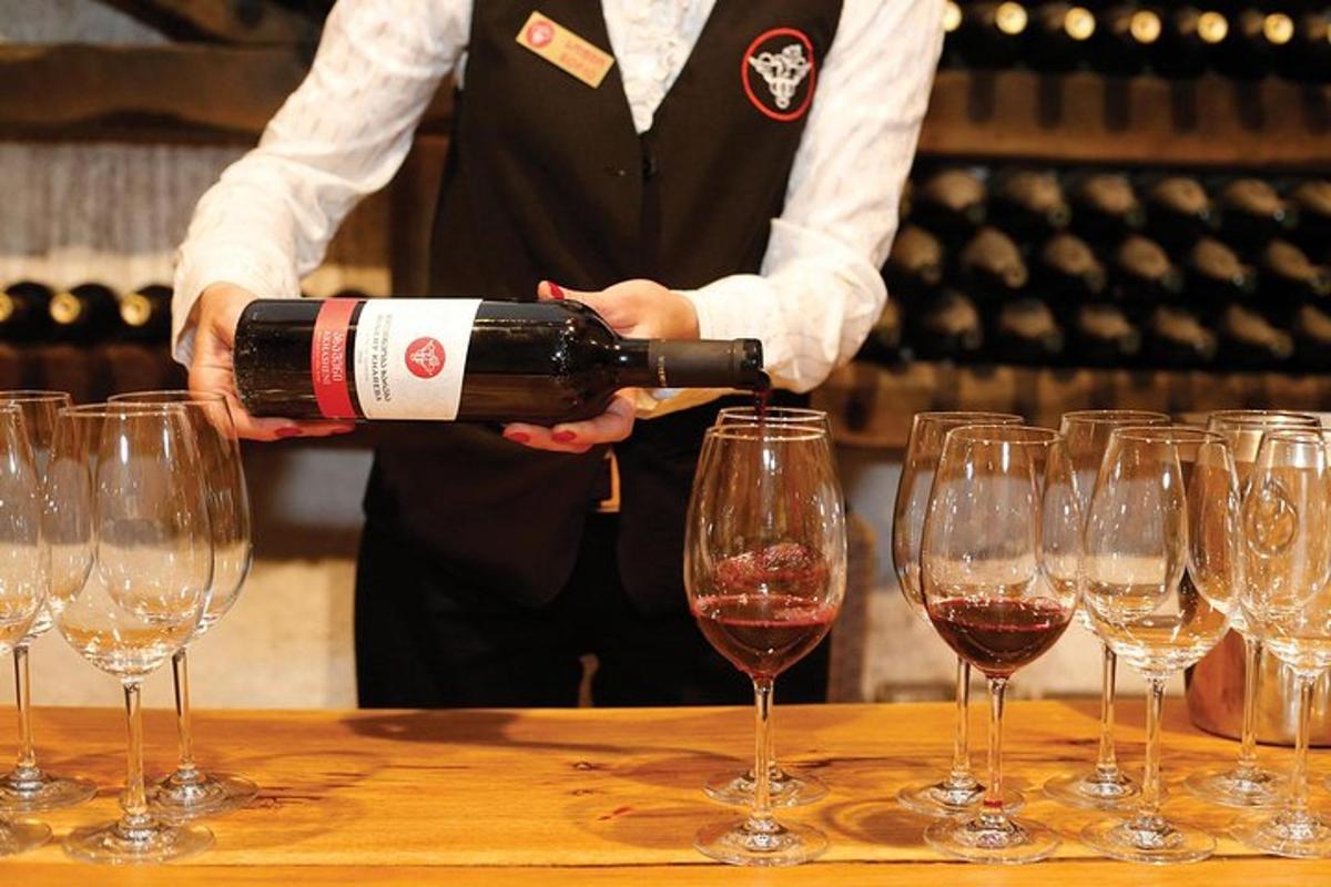 moški, ki naliva steklenico vina v vrsto vinskih kozarcev