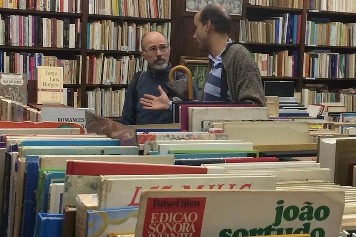 dois homens em pé em uma biblioteca olhando livros