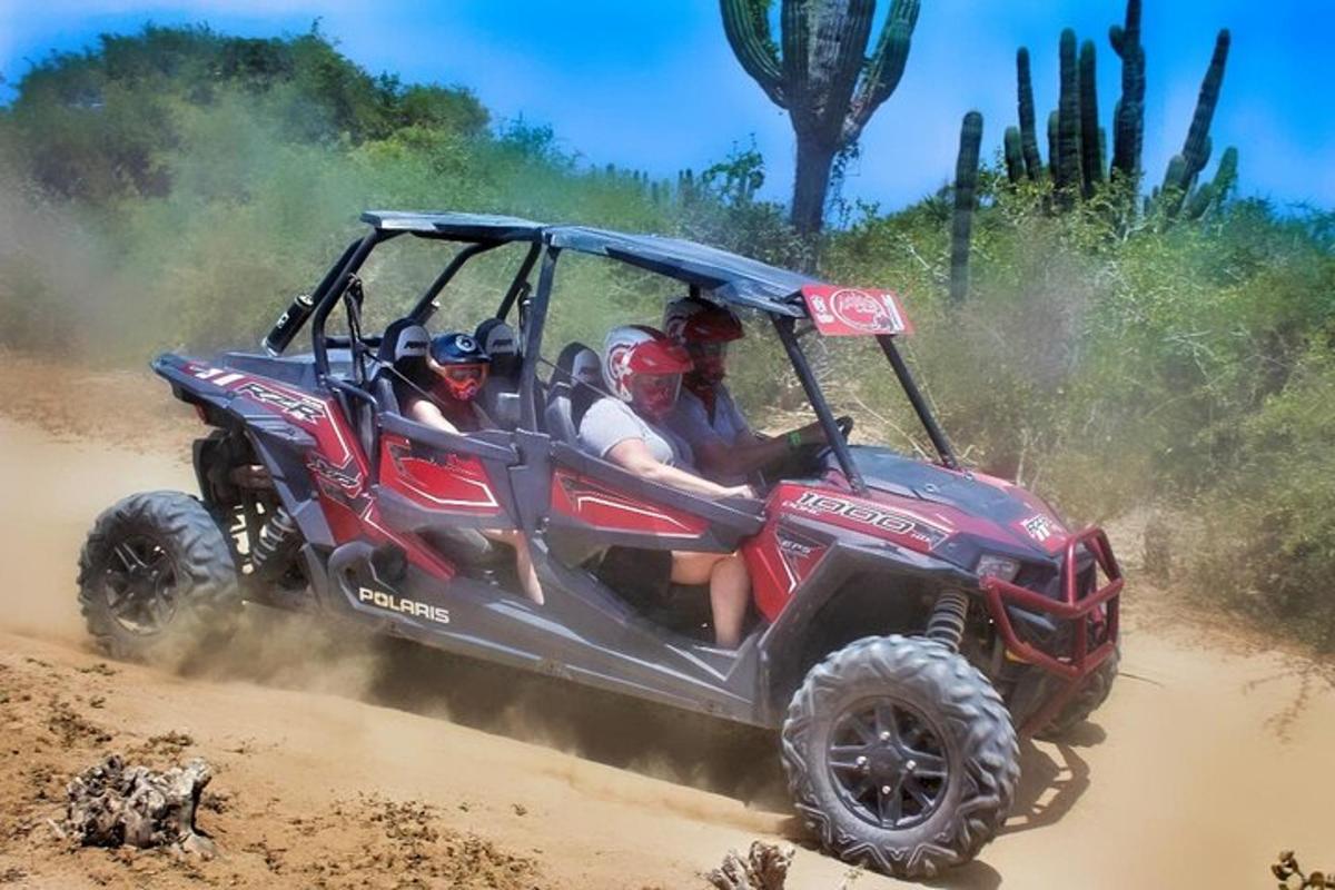 a group of people riding in a red atv in the dirt