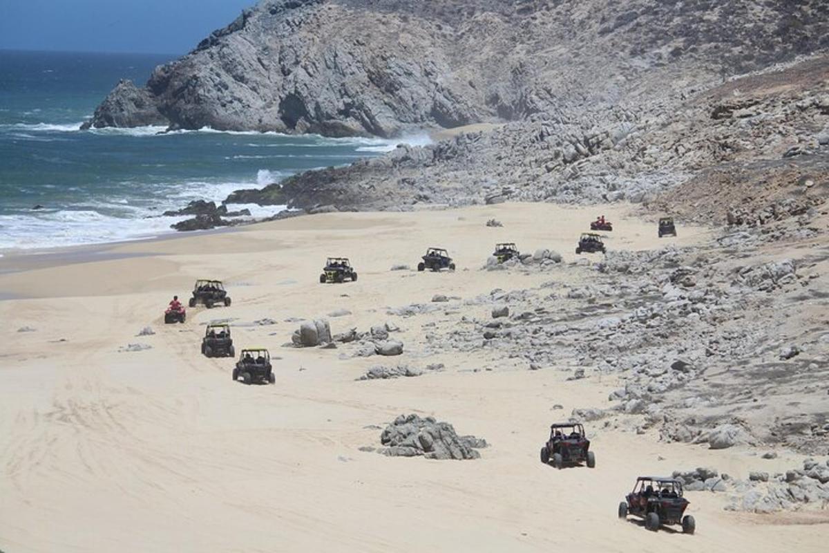 a group of jeeps on a beach near the ocean