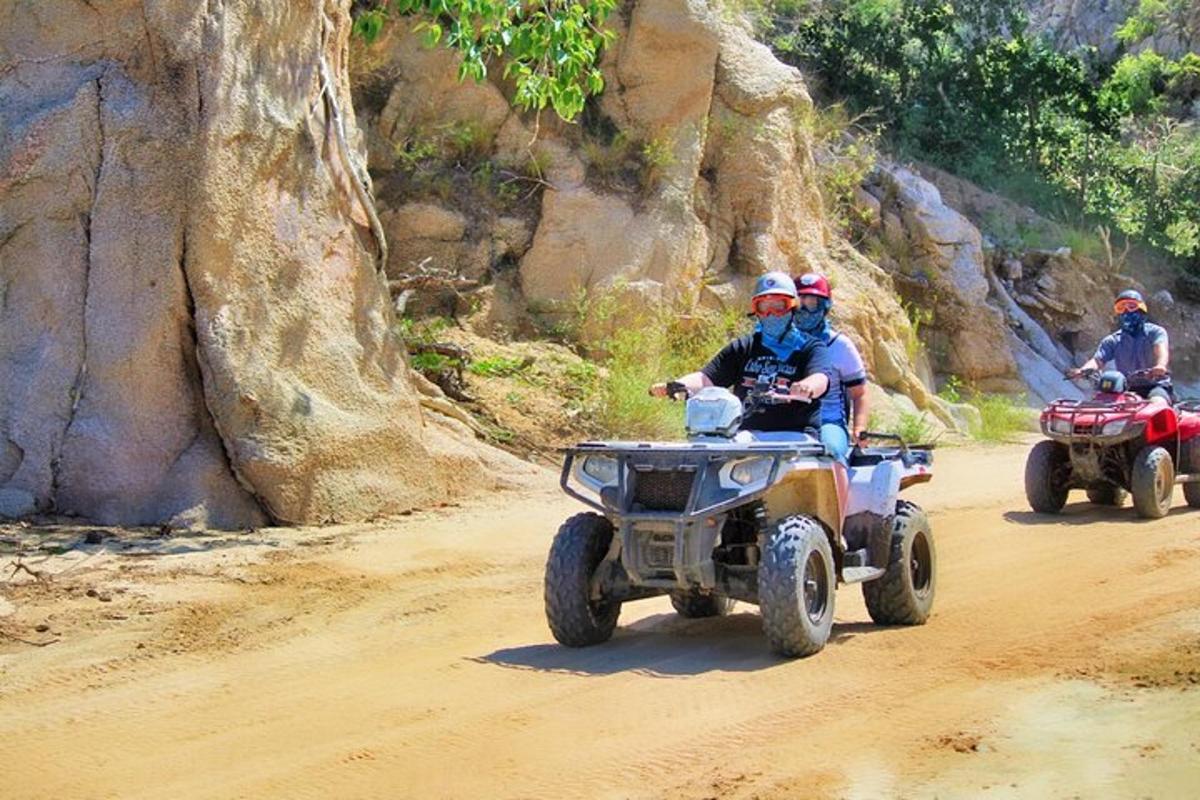 tiga orang menaiki atv di jalan tanah