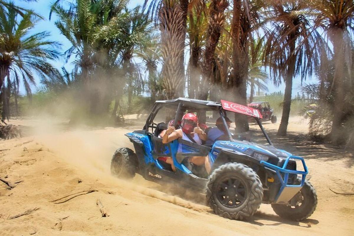 two people riding on a atv in the dirt
