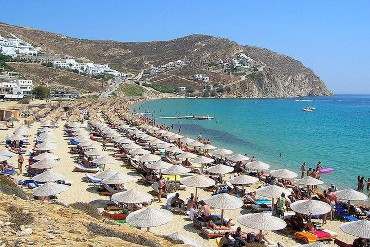 μια ομάδα ανθρώπων που κάθονται σε μια παραλία με ομπρέλες