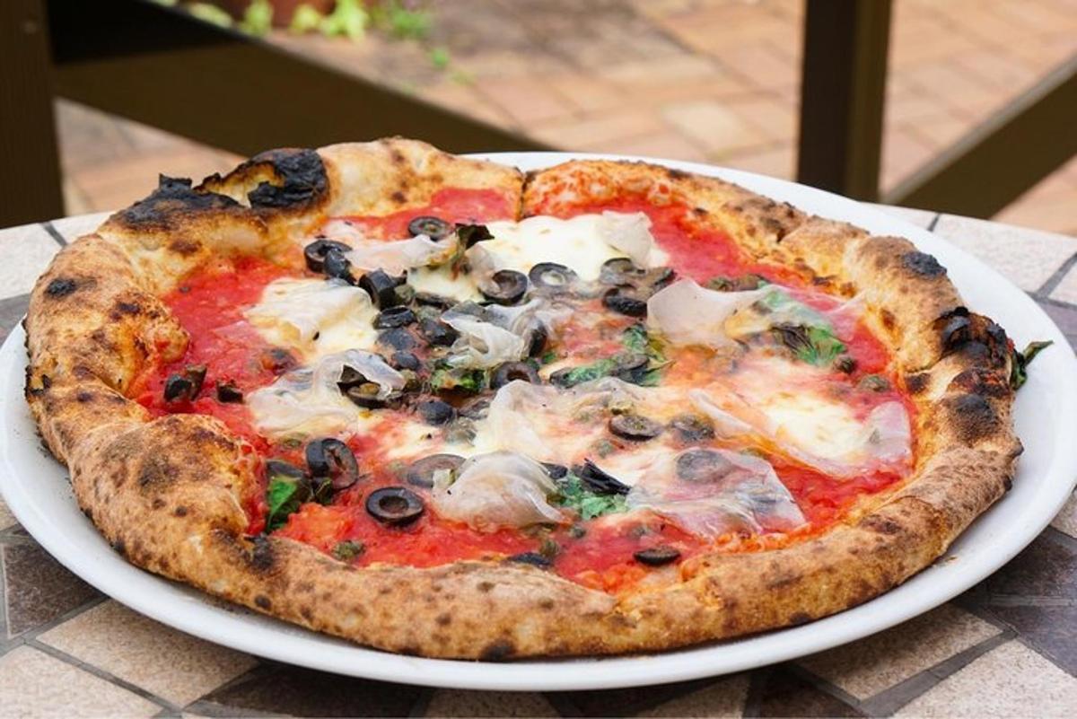 en pizza som står på en hvit tallerken på et bord