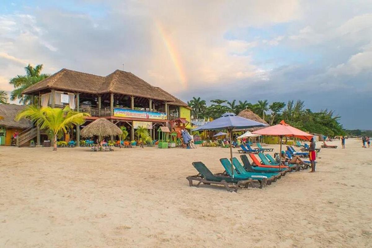 a rainbow over a beach with chairs and umbrellas