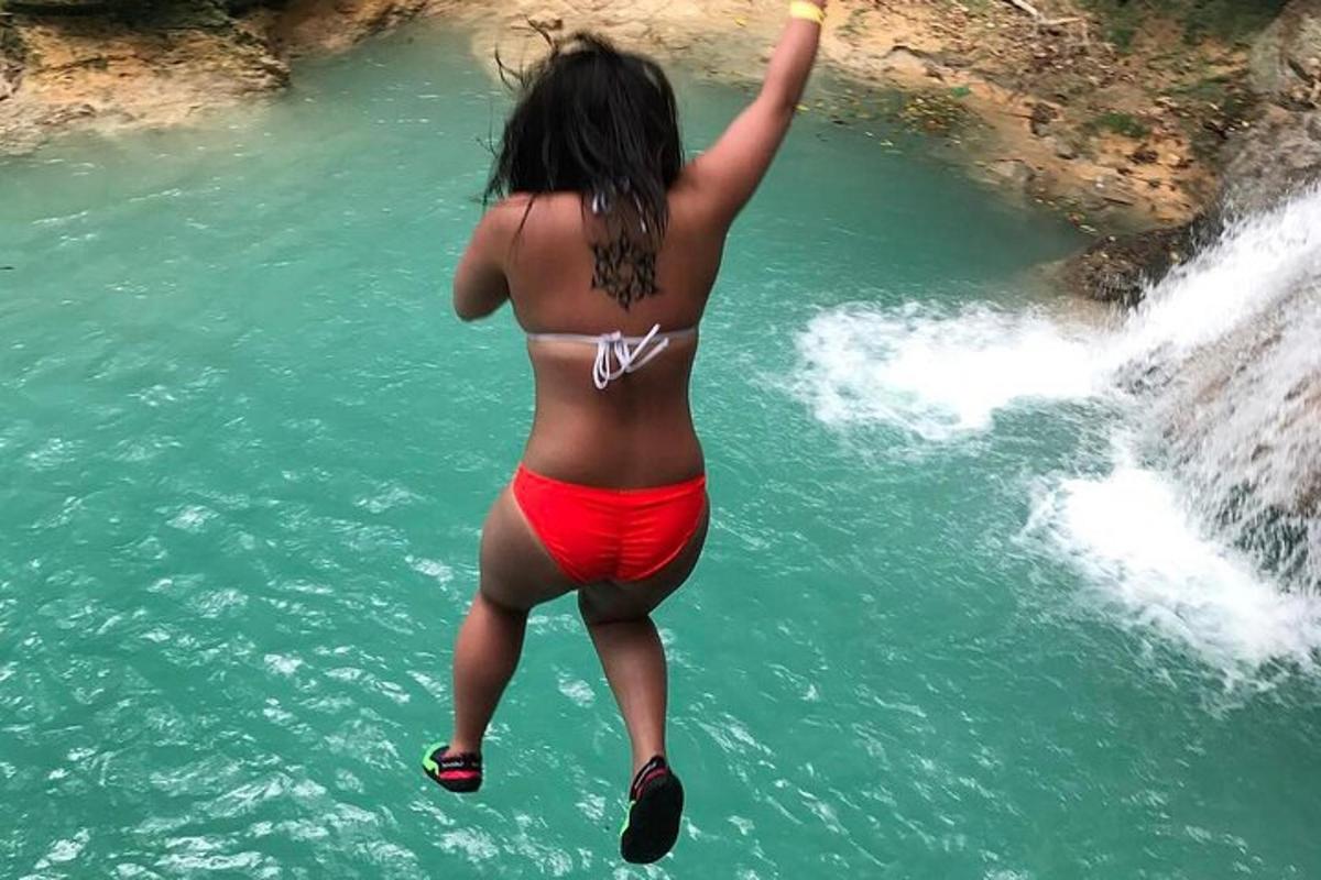 una donna in bikini che salta in una cascata