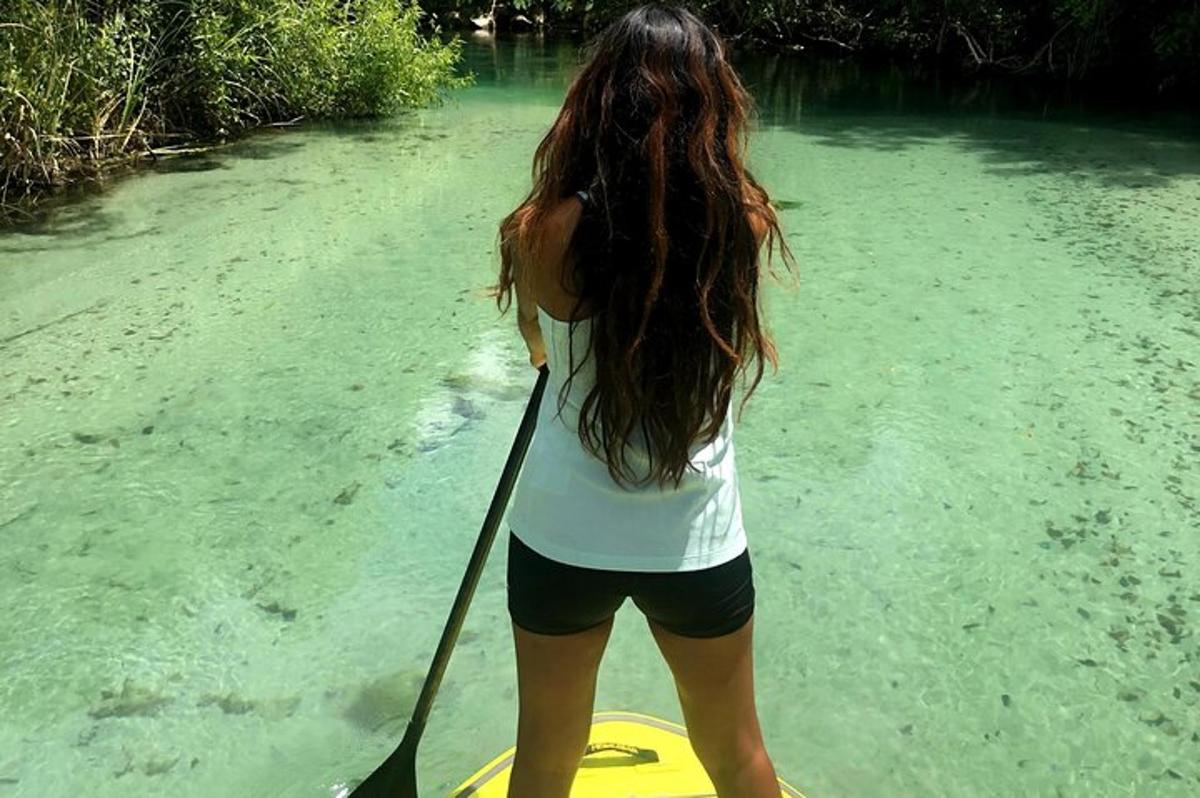 žena stojící na paddleboardu ve vodě