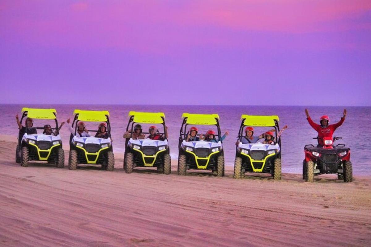 een groep van vier personen die op quads over het strand rijden