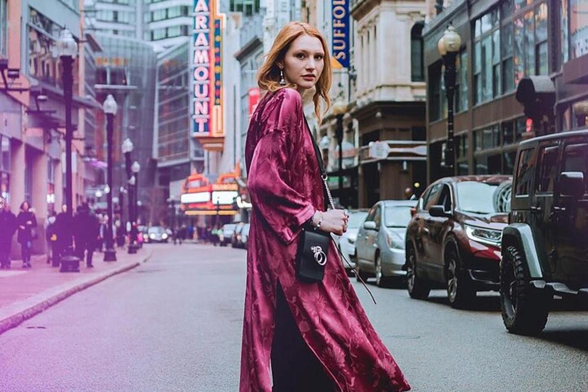 una donna che cammina lungo una strada cittadina indossando un vestito viola
