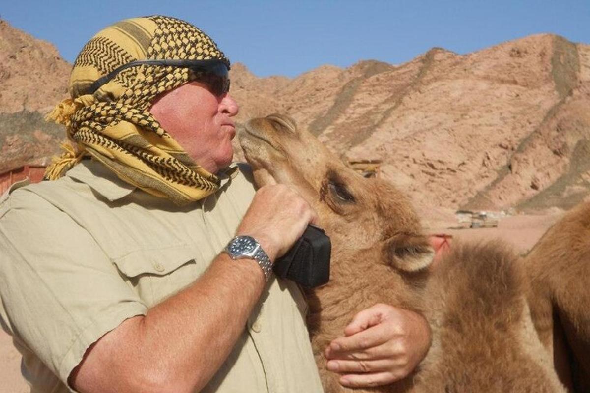 رجل يقبل جملًا في الصحراء