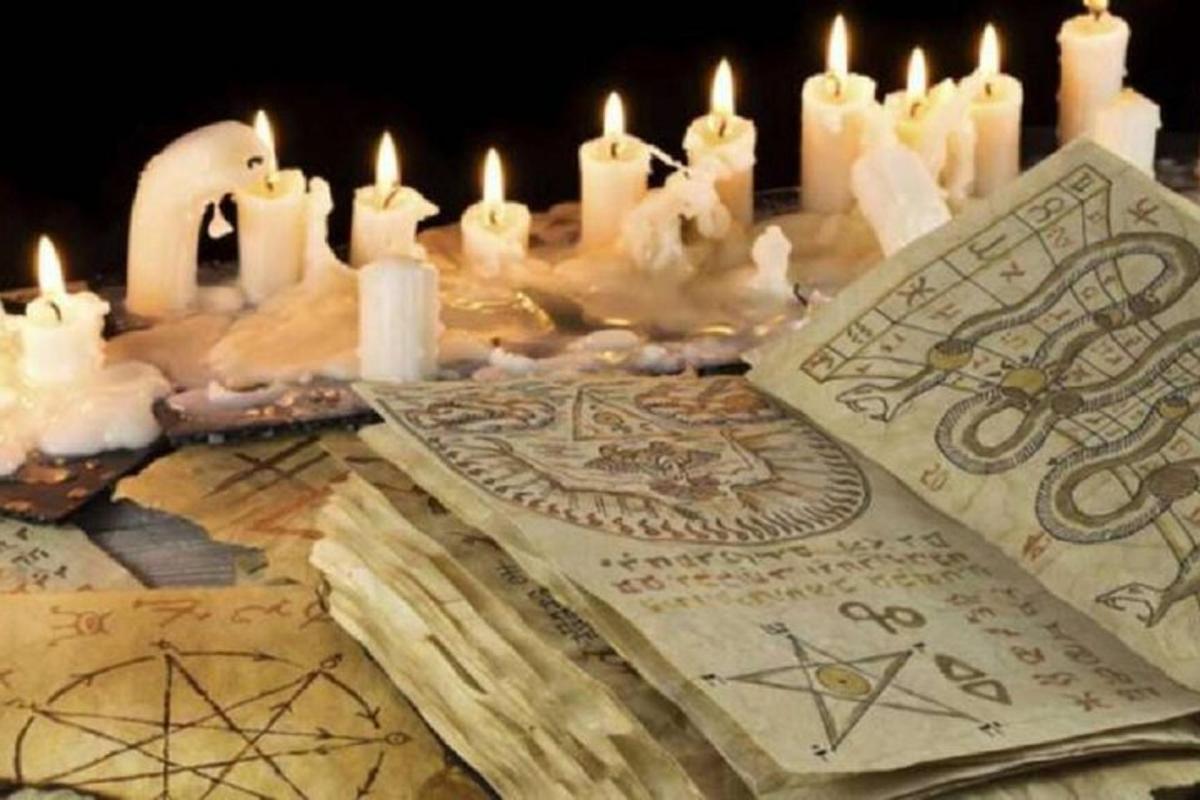 a table topped with candles and a book with occult signs