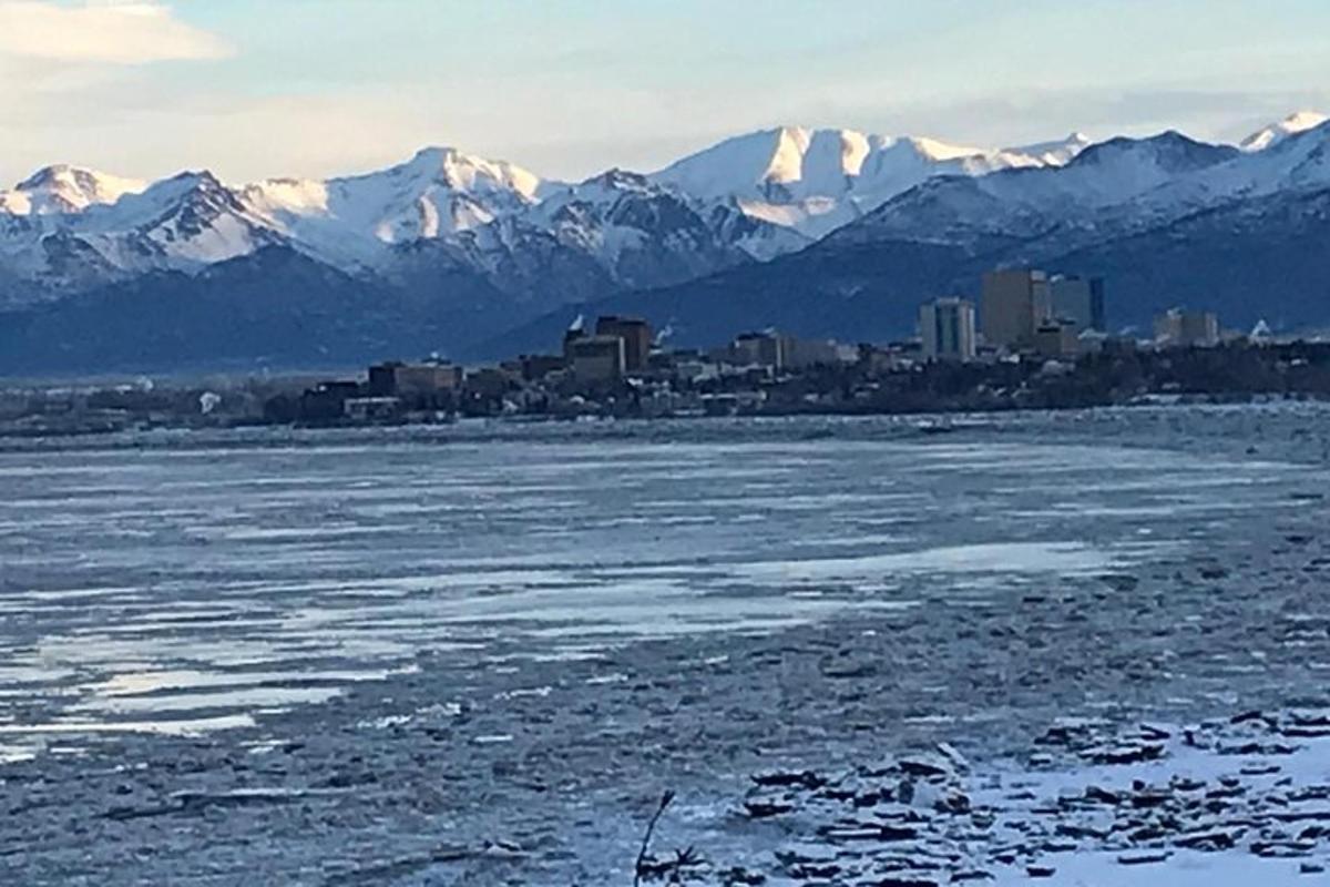 una gran massa d'aigua amb una ciutat i muntanyes cobertes de neu