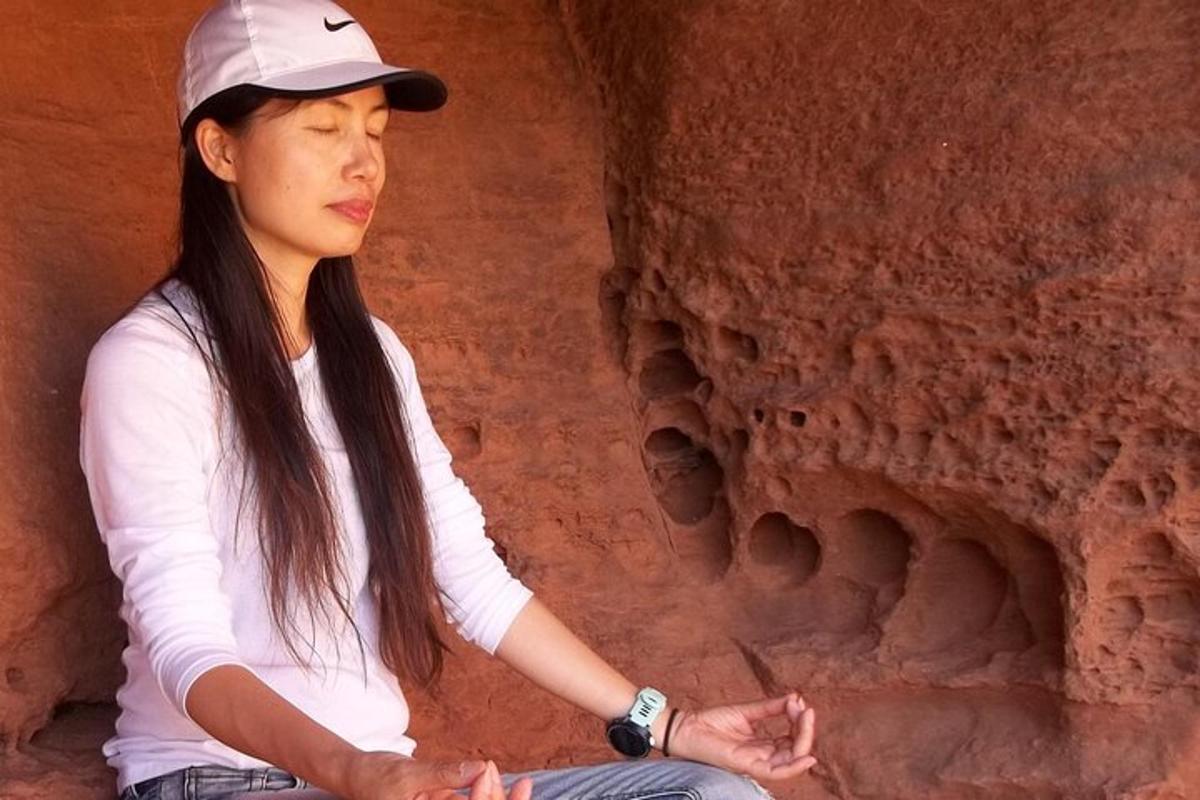 ženska, ki sedi v meditaciji pred skalno formacijo