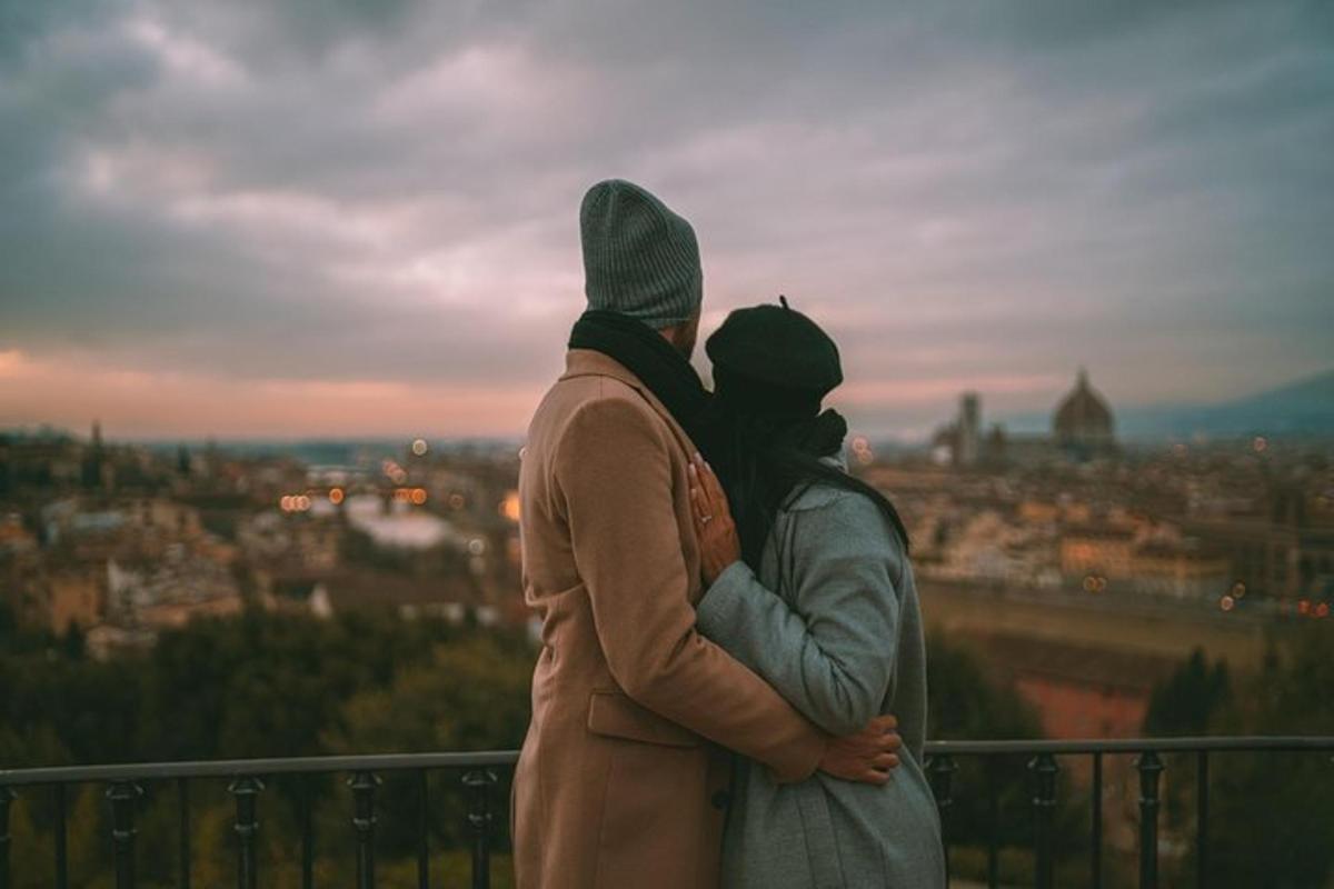 a man and woman standing on a balcony looking at a city