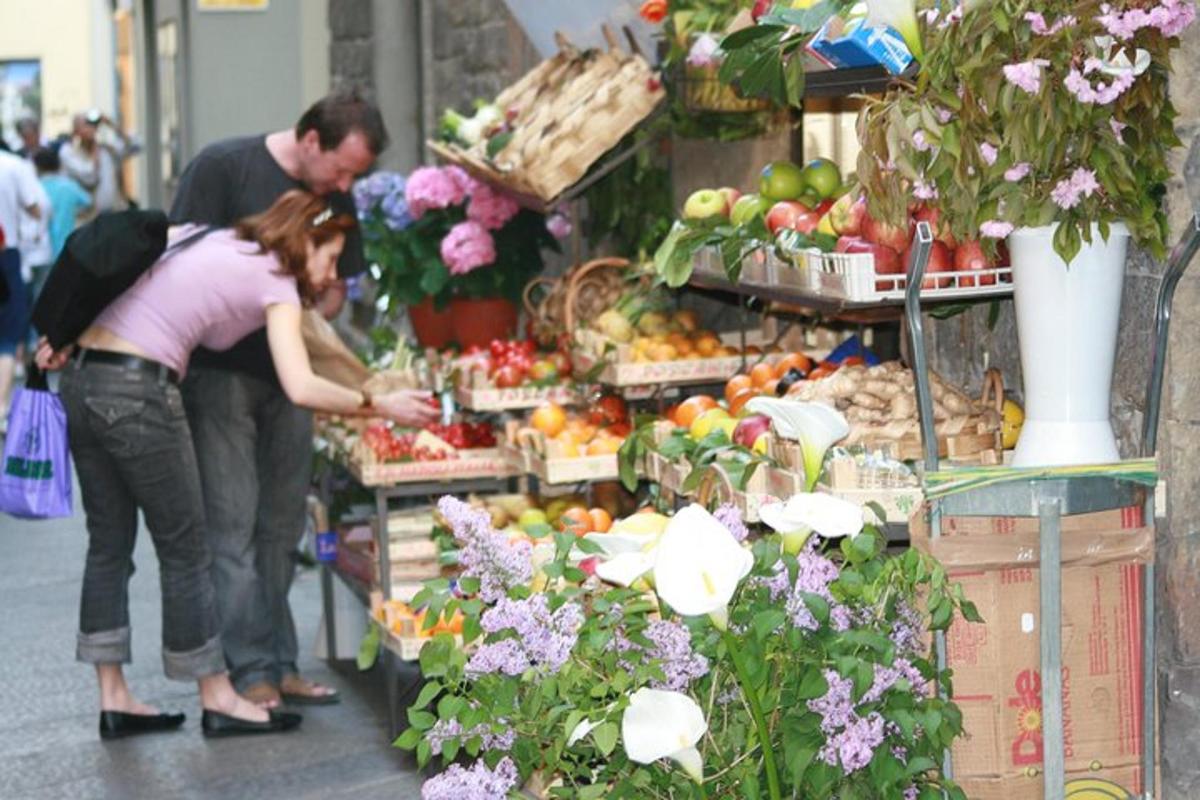 un bărbat și o femeie care se uită la fructe și legume într-o piață