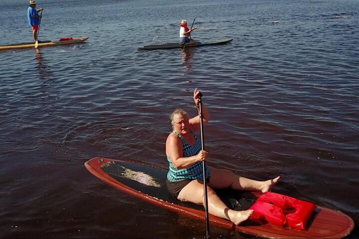en kvinne som sitter på et padlebrett i vannet