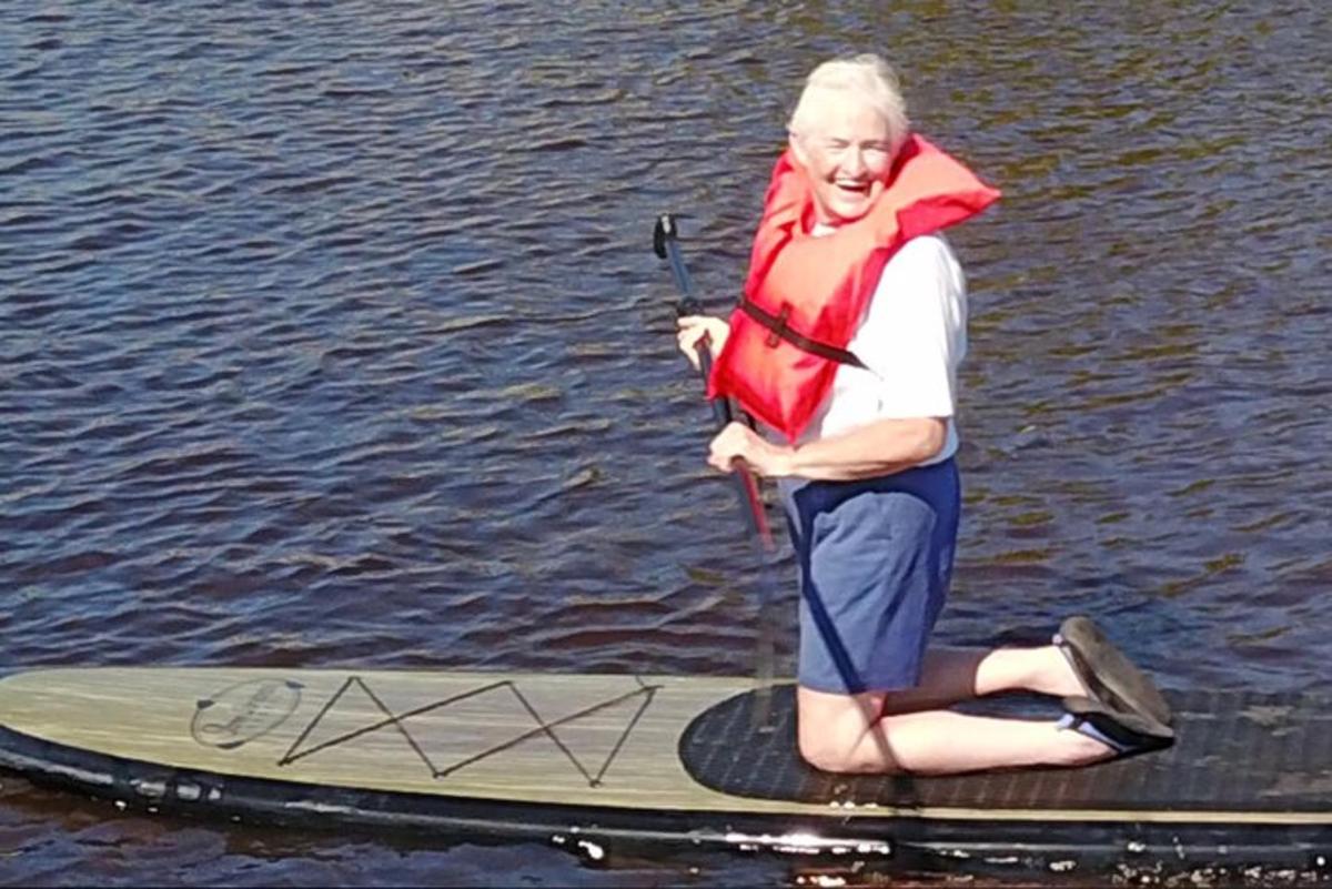 žena stojící na paddleboardu na vodě