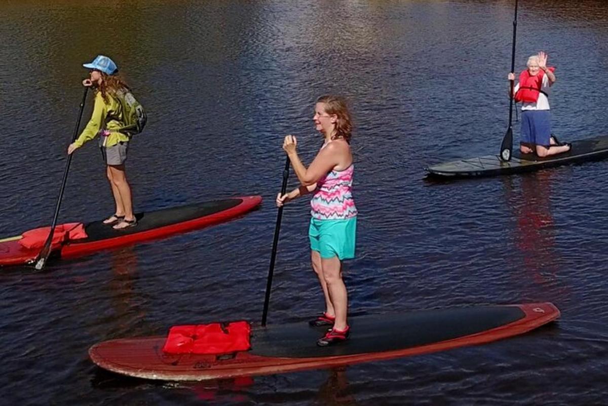 tři lidé stojí na paddleboardech ve vodě